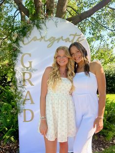 two women standing next to each other in front of a sign that reads congrats grad