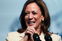 a woman is smiling and holding her hands up in front of the camera while standing behind microphones