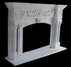 a white marble fireplace mantel with carvings on the top and sides, against a black background