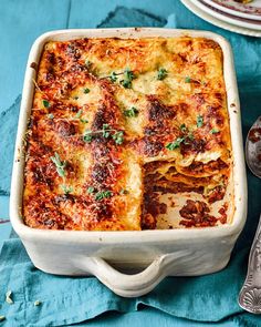 a casserole dish with meat and cheese in it on a blue table cloth