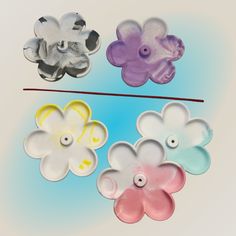 four different colored flower shaped buttons on a white and blue background with one button facing the camera