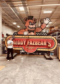 a man standing in front of a sign that says reddy fazebe's pizza