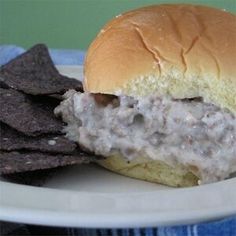 a white plate topped with a sandwich and chips next to a bowl of tortilla chips