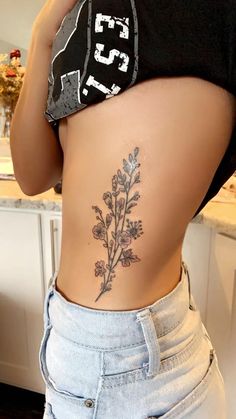 the back of a woman's stomach with flowers tattooed on her lower body and side