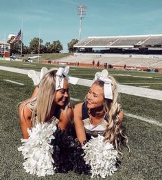 two cheerleaders sitting on the football field