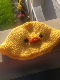 a crocheted yellow ducky hat sitting on top of a window sill