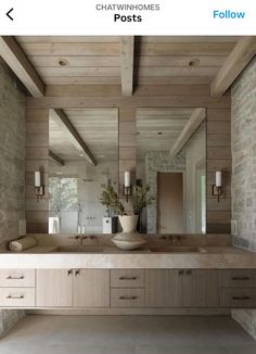 a bathroom with two sinks and mirrors in it's center, next to a brick wall