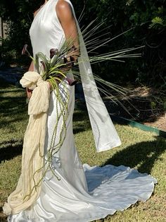 a woman in a white dress is holding a bouquet and wearing a long shawl