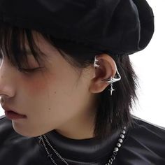 a woman with black hair wearing a hat and piercings on her ear is looking down at the ground