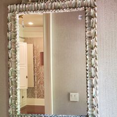 a bathroom mirror reflecting the light in it's reflection on the wall next to a sink