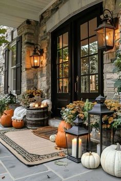 pumpkins and gourds are on the front porch with lanterns, candles and other decorations