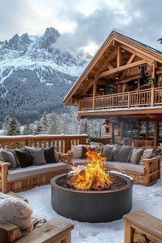 an outdoor fire pit in the middle of snow covered ground with mountains in the background