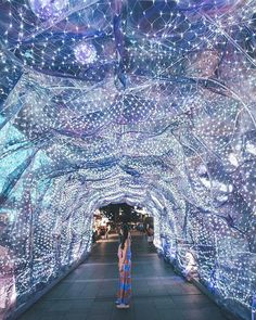 two people standing in front of a tunnel covered with lights