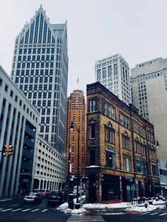 an intersection with buildings and traffic lights in the snow on a city street, surrounded by tall skyscrapers