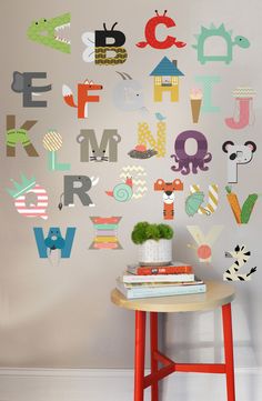 a table with some books on top of it next to a wall that has letters and animals painted on it