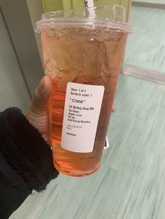 a person holding up a cup of tea with a label on it's side