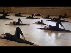 a group of women in black leotards doing stretching exercises on the floor with their hands together