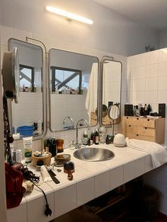 a bathroom sink with three mirrors and other items on the counter in front of it