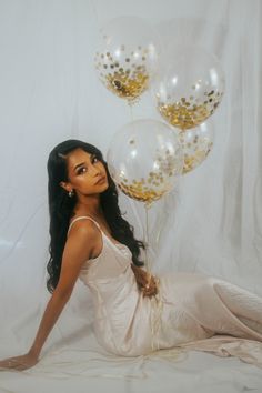 a woman sitting on the floor with balloons in front of her and posing for a photo