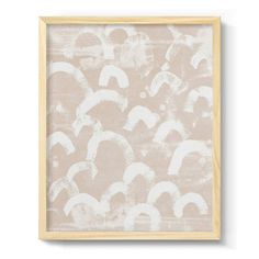 an abstract painting with white paint on beige paper, framed in a wooden frame against a white wall