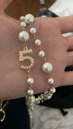 a woman's hand wearing a bracelet with pearls and a number 5 on it