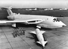 an air force jet sitting on top of an airport tarmac with men standing next to it