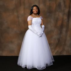 a woman in a white dress and gloves posing for the camera with her hands on her hips