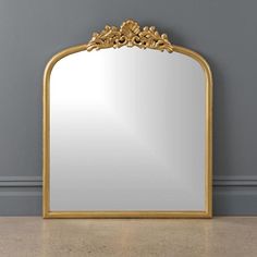 a mirror sitting on top of a floor next to a wall with a gold frame