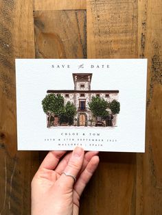 a hand holding up a save the date card with an image of a house on it