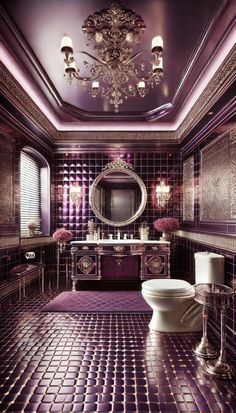 a fancy bathroom with purple tile and chandelier above the toilet, along with two sinks