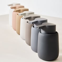 several different colored vases lined up on a white surface with one in the middle