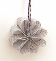 an ornament made out of silver paper on a white surface with a black cord