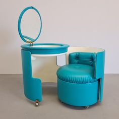 a blue chair sitting next to a round table with a mirror on top of it