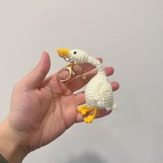 a hand holding two tiny crocheted birds in it's palm, one is yellow and the other is white