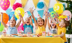 children at a birthday party with balloons and confetti on their heads, holding hands in the air