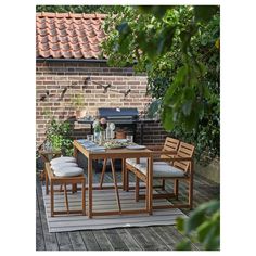 an outdoor table and chairs on a wooden deck next to a brick wall with a grill in the background