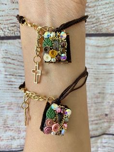 two bracelets with cross charms and beads on the wrist, one is decorated with flowers