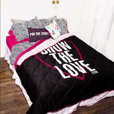 a bed with black and pink comforter, pillows and pillow cases on top of it