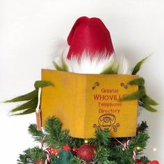 an elf's hat is sitting on top of a christmas tree with a book