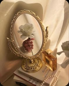 there is a mirror with a flower in it on top of some books and pearls