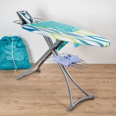 an ironing board is sitting on top of a stand next to a blue bag