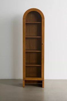 a wooden bookcase with an arched door on the top and bottom shelf, in front of a white wall