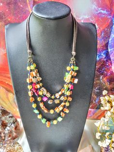 This unique necklace features a beautiful asymmetrical shell pendant on a multicolor beaded waterfall design with multiple strands and an adjustable lobster closure. The vintage piece was likely manufactured in the 1980s, though the exact era is unknown. The necklace is perfect for a variety of occasions, including Mother's Day, engagement, wedding, graduation, Christmas, anniversary, Father's Day, birthday, christening/confirmation, and Valentine's Day. It has a bohemian and retro feel, as well as a nod to sea life and ethnic fashion. The necklace is handmade and has an eye-clean gemstone clarity grade. Multi-strand Mother Of Pearl Beaded Necklaces, Elegant Multi-strand Mother Of Pearl Necklace, Multicolor Multi-strand Bohemian Necklace, Bohemian Mother Of Pearl Shell-shaped Beaded Necklace, Bohemian Multicolor Shell-shaped Necklace, Waterfall Design, Unique Necklace, Shell Pendant, Multi Strand Necklace