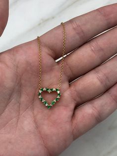 Displayed is a gorgeous 0.55tcw natural emerald and diamond heart necklace. Crafted in solid 18K yellow gold, this piece is sure to make a statement. Brilliant round vivid green emeralds and diamonds highlight the heart-shaped necklace. The gems are of excellent color and clarity. An 18-inch cable chain comes with the necklace ♥ Setting Style: Prong/ Pave Setting Material: 18k Yellow Gold Main Stone: Emerald Shape: Round Weight: 0.33-carats Clarity: Excellent-Very Good Color: Green Luster: Excel Heart Cut Emerald Necklace For Gift, Heart-shaped Emerald Necklaces For Anniversary, Heart-shaped Emerald Necklace For Anniversary, Heart-shaped Emerald Gemstone Necklace, Emerald Heart Shaped Gemstone Necklace, Emerald Heart Gemstone Necklace, Anniversary Heart-shaped Emerald Necklace, Gold Heart-cut May Birthstone Necklaces, Heart Cut Emerald Necklaces For May Birthstone