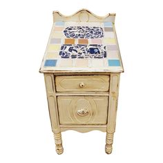 an old wooden table with colorful tiles on it's top and bottom drawer, against a white background