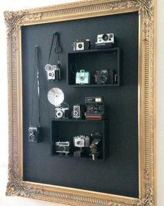 there are many cameras on display in the frame and behind it is a black board with gold trim