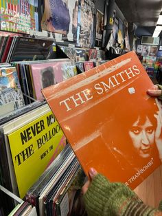 a person holding up an orange vinyl album