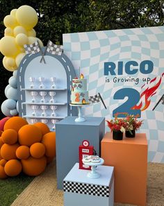 there is a sign that says rico is growing up and two cakes on pedestals