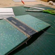 an open notebook sitting on top of a table next to scissors and other crafting supplies