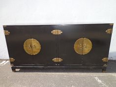 a black and gold cabinet sitting on top of a cement floor next to a white wall